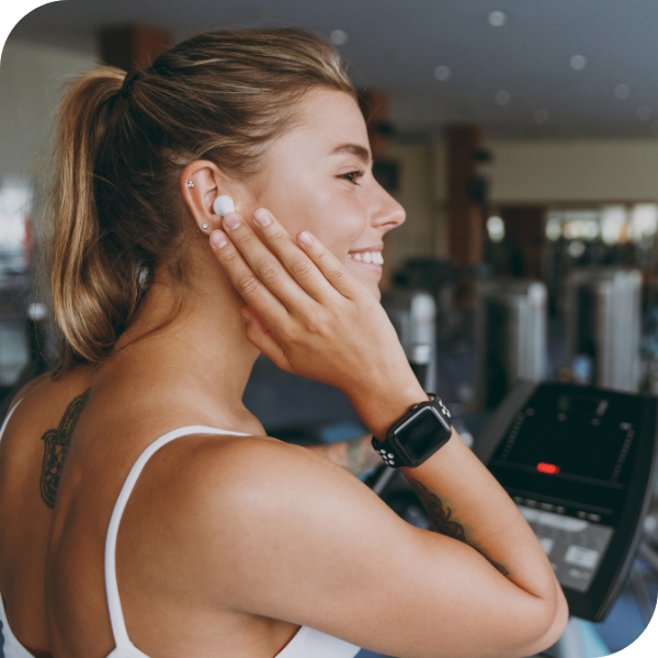 Woman listening to workout music on digital fitness connected device with earbud